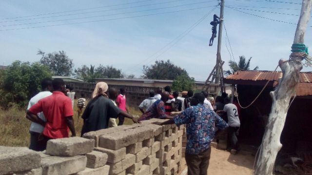 Tragic: People watch in horror as the electrocuted remains of Ben Nunoo hung from the electricity pole in Sege