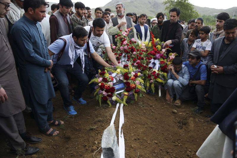 Relatives, colleagues and friends puts flowers on the grave of AFP chief photographer, Shah Marai, who was killed in the Kabul attack. (Photo: AP)